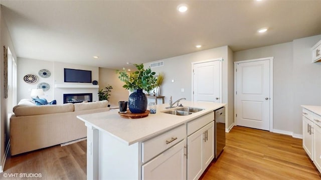 kitchen featuring white cabinets, light hardwood / wood-style floors, sink, and an island with sink