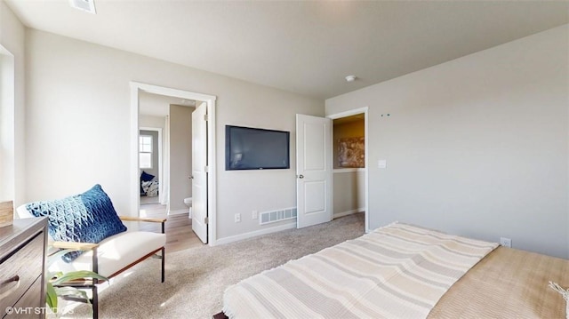 bedroom featuring connected bathroom and light carpet