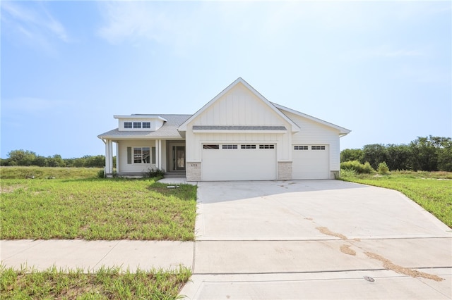 view of front of home featuring covered porch, a garage, and a front yard