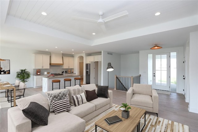 1772 Highland Cir SW, Altoona, IA 50009 - living room featuring light wood finished floors, a tray ceiling, recessed lighting, ceiling fan, and arched walkways