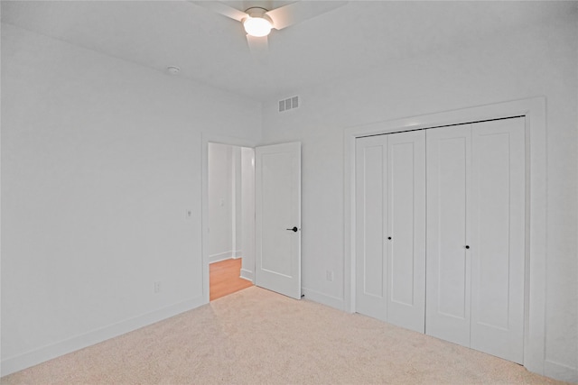 unfurnished bedroom featuring ceiling fan, light colored carpet, and a closet