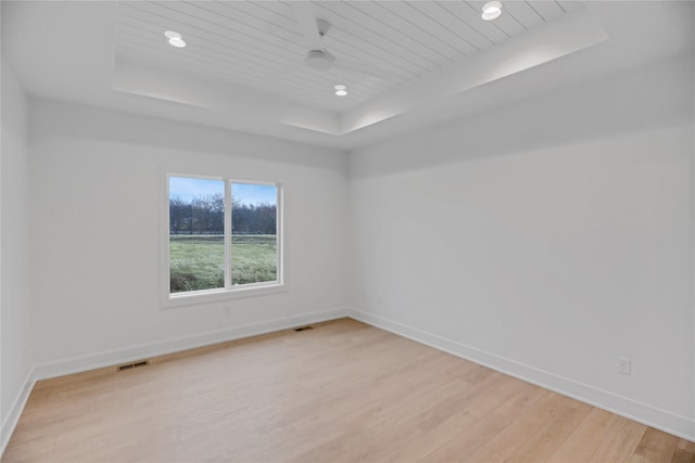 empty room with light hardwood / wood-style floors and a raised ceiling