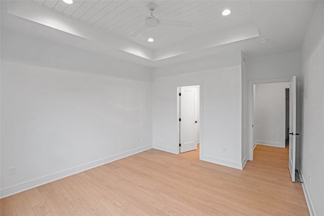 unfurnished bedroom featuring a raised ceiling and light hardwood / wood-style floors