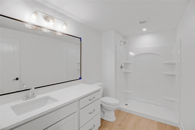 bathroom with a shower, hardwood / wood-style floors, vanity, and toilet