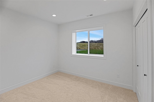 unfurnished bedroom featuring a closet and light colored carpet