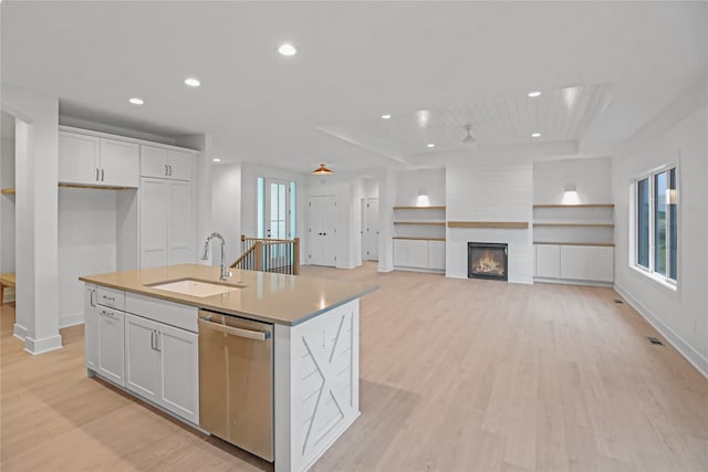 kitchen with white cabinetry, a kitchen island with sink, sink, and stainless steel dishwasher