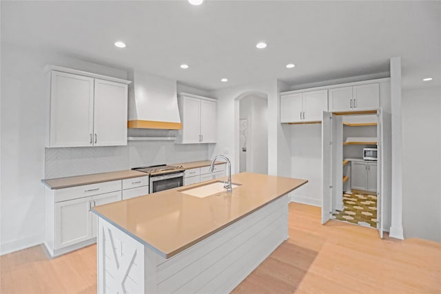 1772 Highland Cir SW, Altoona, IA 50009 - kitchen featuring custom range hood, a sink, stainless steel appliances, arched walkways, and light wood-type flooring