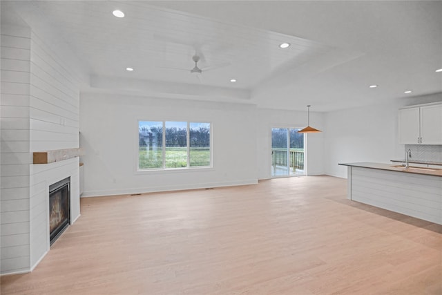 unfurnished living room featuring light hardwood / wood-style flooring, ceiling fan, and sink