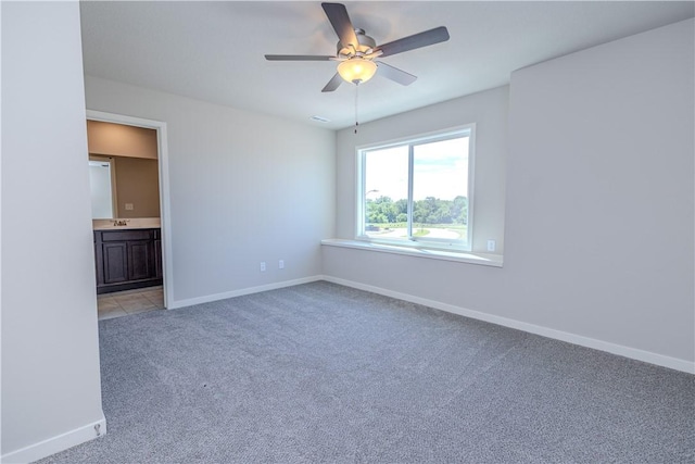 carpeted spare room featuring ceiling fan and sink