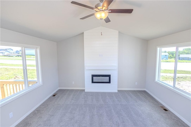 unfurnished living room featuring carpet, ceiling fan, a fireplace, and vaulted ceiling