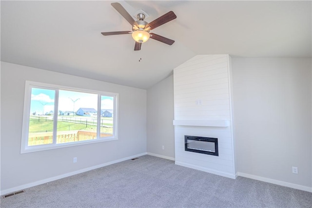 unfurnished living room with ceiling fan, lofted ceiling, a fireplace, and light carpet