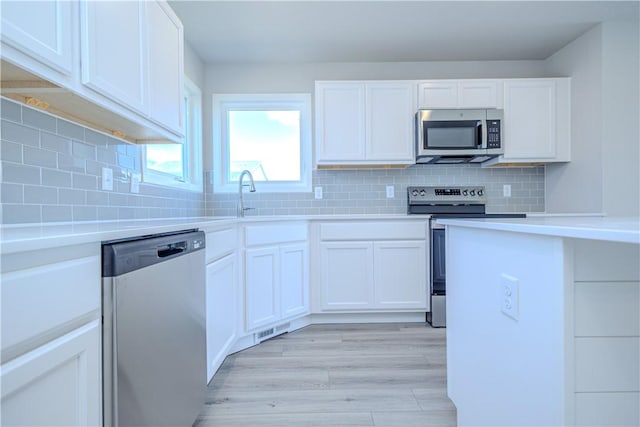 kitchen with sink, white cabinets, stainless steel appliances, and light hardwood / wood-style flooring