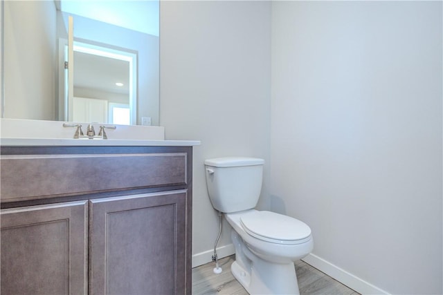 bathroom with hardwood / wood-style floors, vanity, and toilet