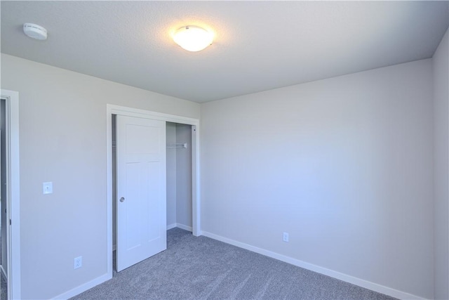 unfurnished bedroom featuring dark carpet and a closet