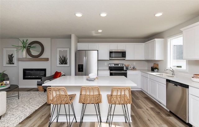 kitchen featuring a center island, a breakfast bar, stainless steel appliances, sink, and light hardwood / wood-style floors