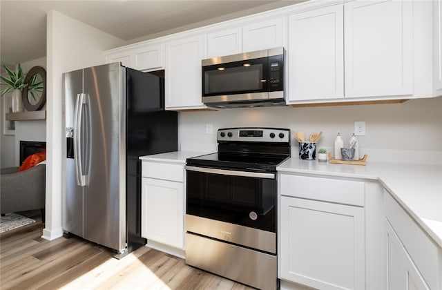 kitchen with appliances with stainless steel finishes, light hardwood / wood-style flooring, and white cabinets