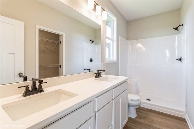 bathroom with hardwood / wood-style floors, vanity, toilet, and walk in shower