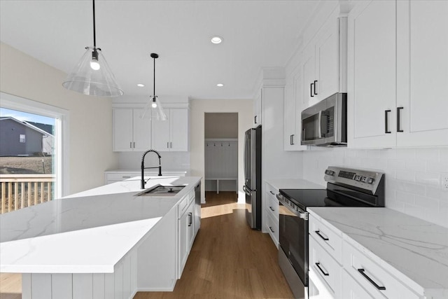 kitchen with decorative light fixtures, white cabinetry, an island with sink, sink, and stainless steel appliances