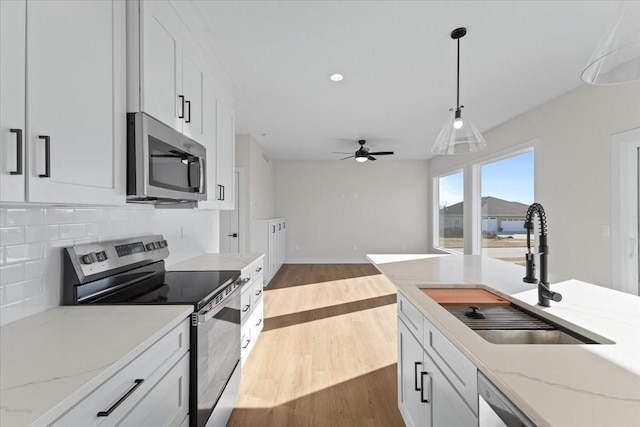 kitchen with white cabinetry, appliances with stainless steel finishes, sink, and backsplash