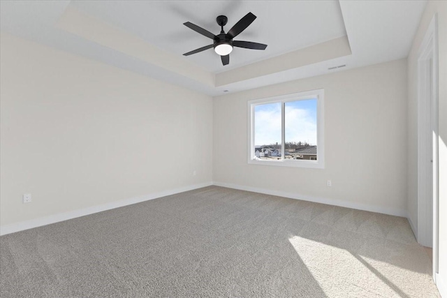 carpeted empty room with a tray ceiling and ceiling fan