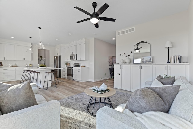 living room with light hardwood / wood-style floors and ceiling fan