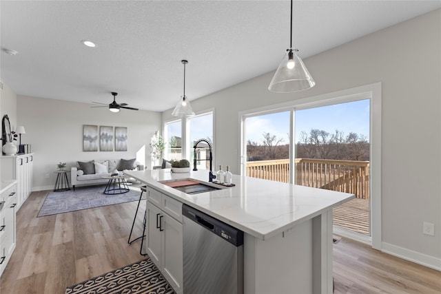 kitchen with sink, stainless steel dishwasher, pendant lighting, a kitchen island with sink, and white cabinets