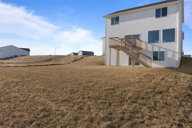 rear view of house with a wooden deck and a lawn