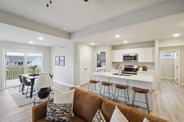 kitchen with white cabinets, light wood-type flooring, and stainless steel appliances