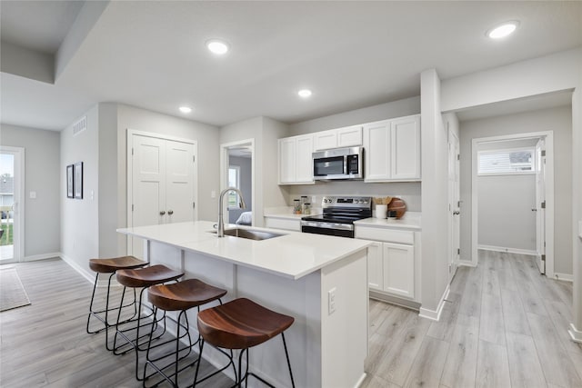 kitchen with white cabinetry, a center island with sink, stainless steel appliances, and sink