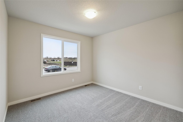 carpeted spare room featuring a textured ceiling