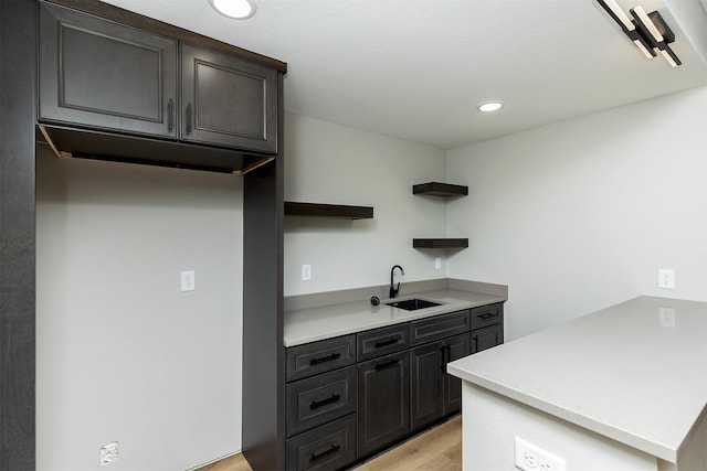 kitchen with dark brown cabinetry, light hardwood / wood-style floors, and sink