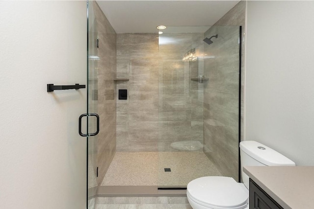 bathroom with vanity, a shower with door, and toilet