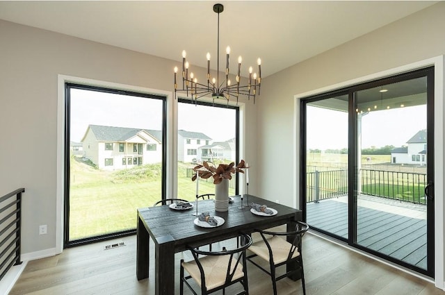 dining space with light hardwood / wood-style floors and a chandelier