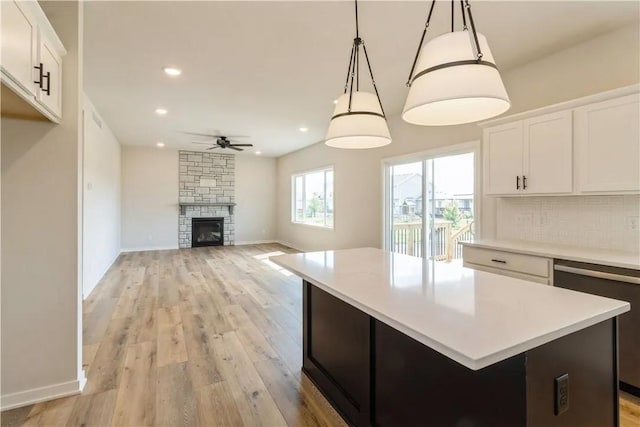 kitchen featuring white cabinets, dishwashing machine, a center island, hanging light fixtures, and light countertops