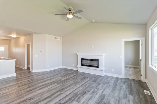 unfurnished living room with a healthy amount of sunlight, ceiling fan, hardwood / wood-style flooring, and lofted ceiling