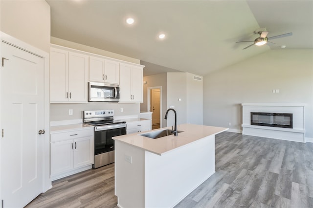 kitchen with white cabinetry, stainless steel appliances, sink, and an island with sink