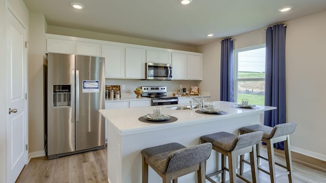 kitchen featuring white cabinetry, stainless steel appliances, light wood-type flooring, and a sink