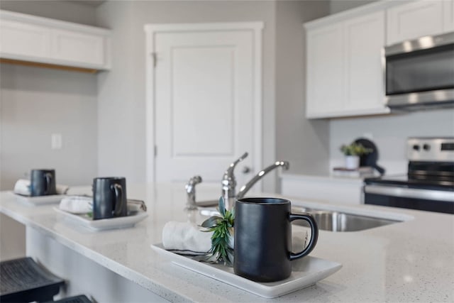 kitchen featuring light stone counters, sink, white cabinets, and stainless steel appliances