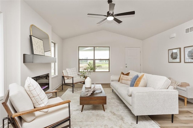 living room featuring ceiling fan, light hardwood / wood-style flooring, and vaulted ceiling