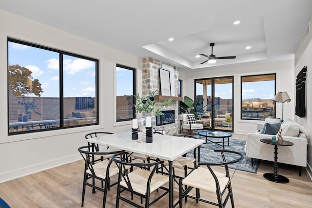 dining room with a tray ceiling, ceiling fan, plenty of natural light, and light hardwood / wood-style floors