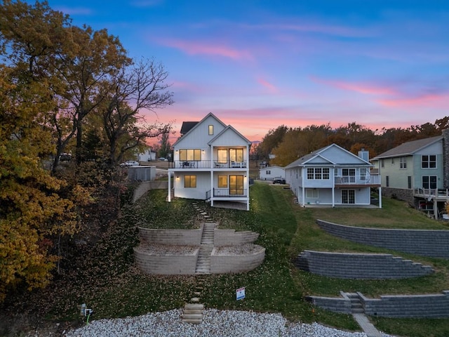 back of house featuring a lawn and a balcony