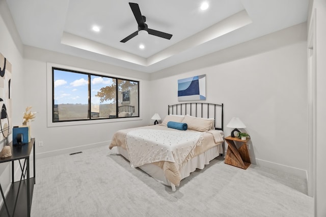 carpeted bedroom featuring a raised ceiling and ceiling fan