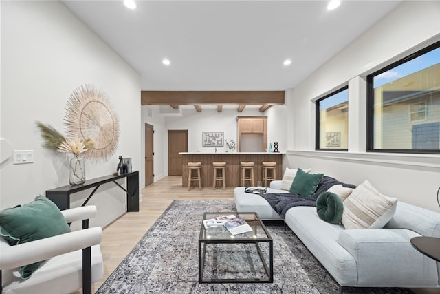 living room featuring beam ceiling, bar area, and light hardwood / wood-style floors