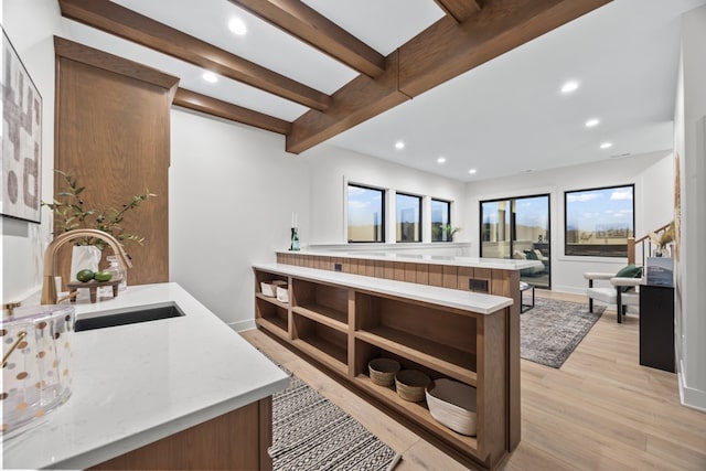 kitchen featuring beamed ceiling, light hardwood / wood-style flooring, and sink