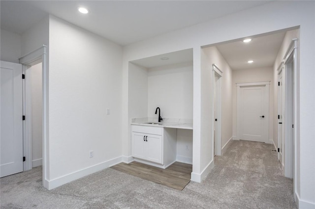 hall featuring light carpet and sink