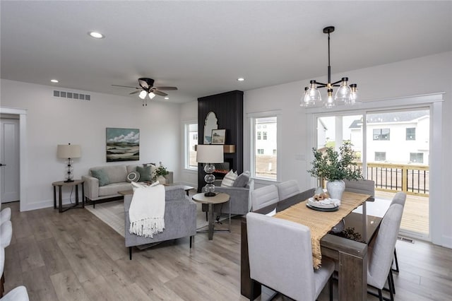 dining room with ceiling fan with notable chandelier and light wood-type flooring