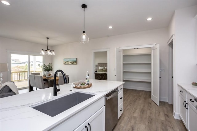 kitchen featuring white cabinets, sink, dishwasher, light hardwood / wood-style floors, and hanging light fixtures