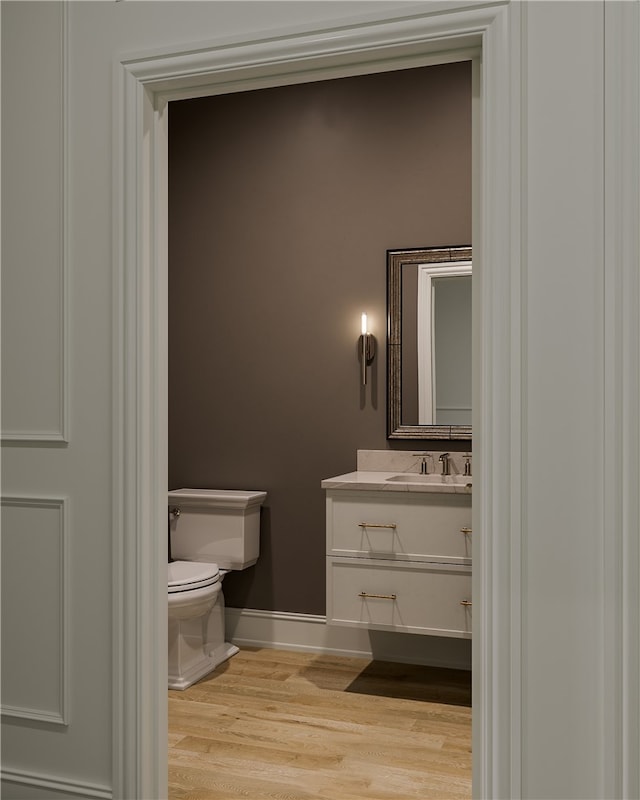 bathroom featuring wood-type flooring, toilet, and vanity