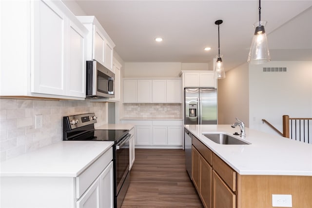 kitchen featuring stainless steel appliances, a center island with sink, dark hardwood / wood-style floors, white cabinetry, and hanging light fixtures