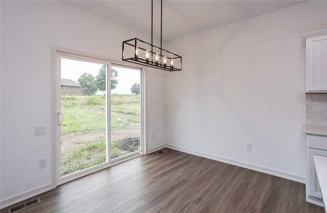 unfurnished dining area featuring wood-type flooring and an inviting chandelier